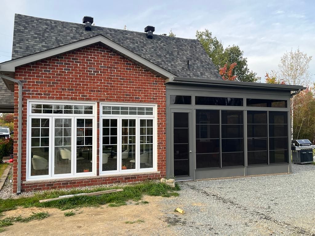 Une maison en briques avec un porche grillagé attenant.