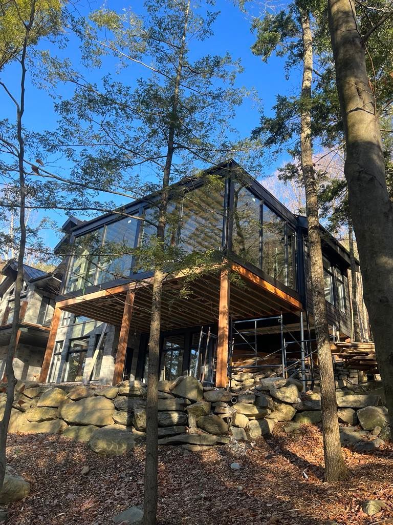 Une maison avec beaucoup de fenêtres est entourée d'arbres.