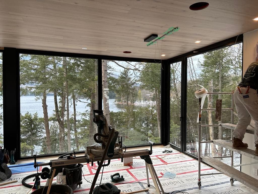 Un homme est debout sur une échelle dans une pièce avec beaucoup de fenêtres.