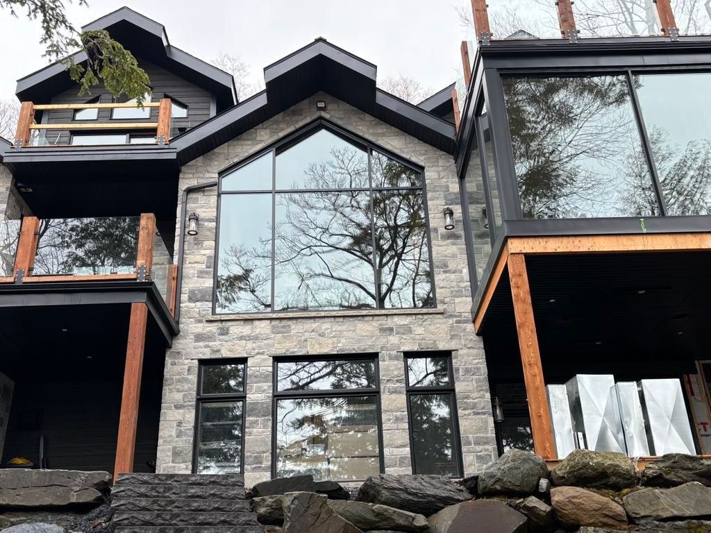 Une grande maison avec beaucoup de fenêtres et des arbres se reflétant dans les fenêtres.