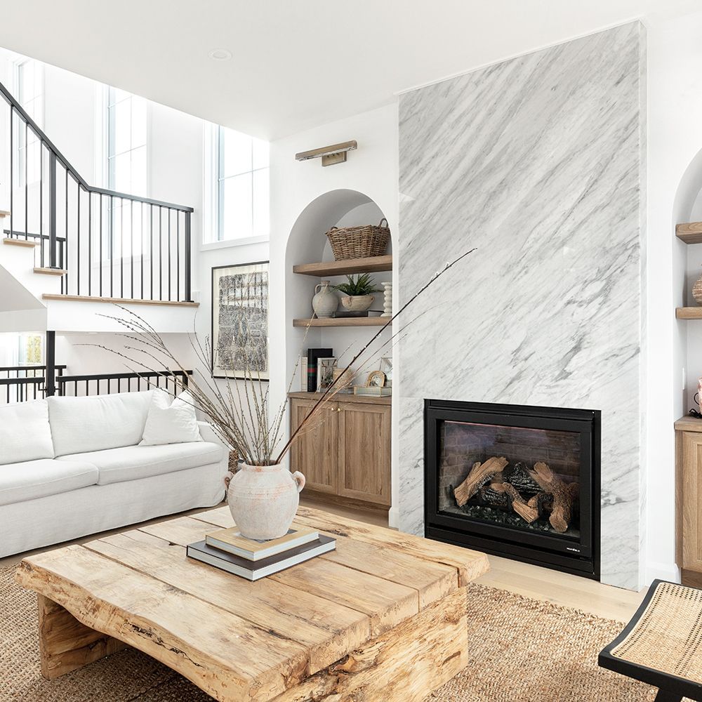 Un salon avec un canapé, une table basse, une cheminée et un escalier.