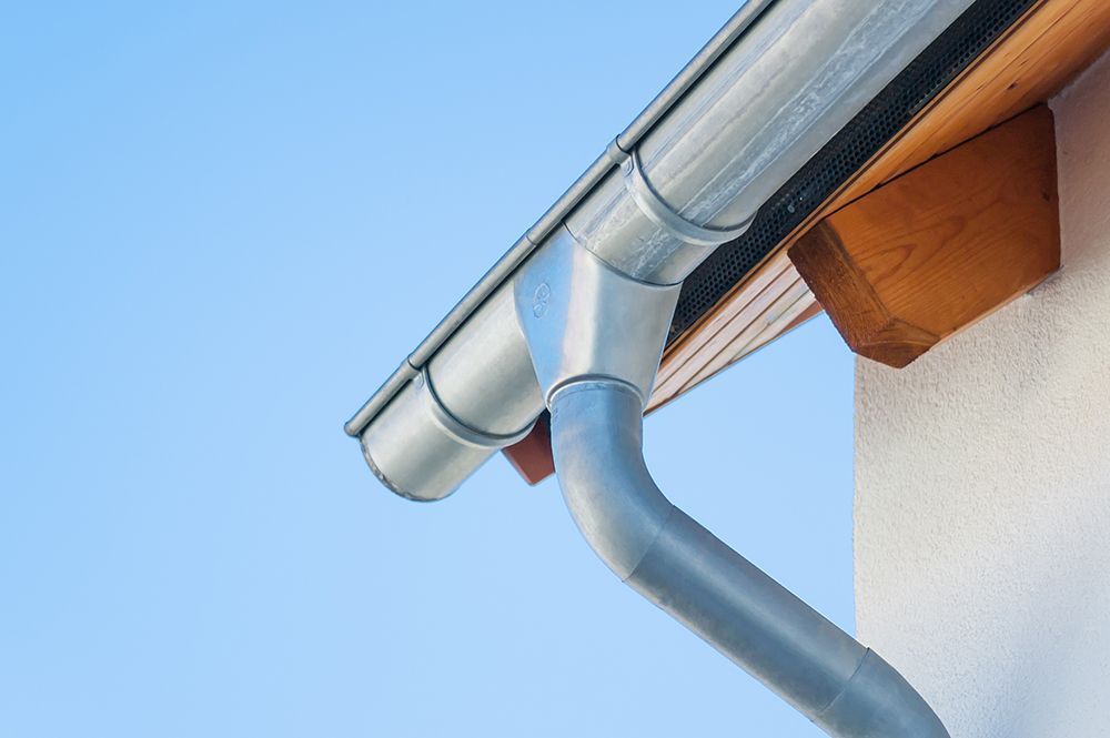 Gray gutter system on a building's edge, blue sky in the background.