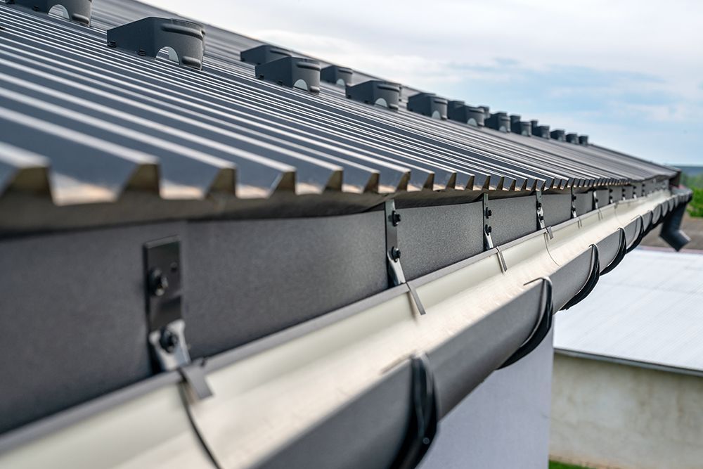 Gray roof with gutter system, brackets and downspout, daylight.