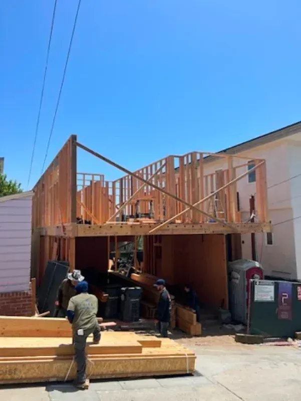 Construction site: Wooden frame of a building under construction; workers present.