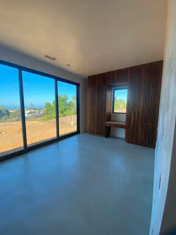 Modern room with large windows, wooden wall paneling, desk, and a scenic outdoor view.