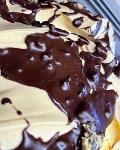 Un primo piano di un gelato cremoso, di colore giallo pallido, con vortici di spesse e lucide strisce di cioccolato fondente.