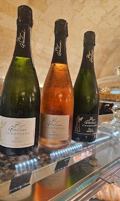Su un bancone espositivo sono esposte tre bottiglie di champagne Pierre Gimonnet & Fils, tra cui una rosata.