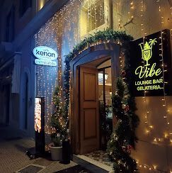 L'ingresso del Vibe Lounge Bar & Gelateria, decorato di notte con lucine scintillanti e due alberi sempreverdi in vaso.