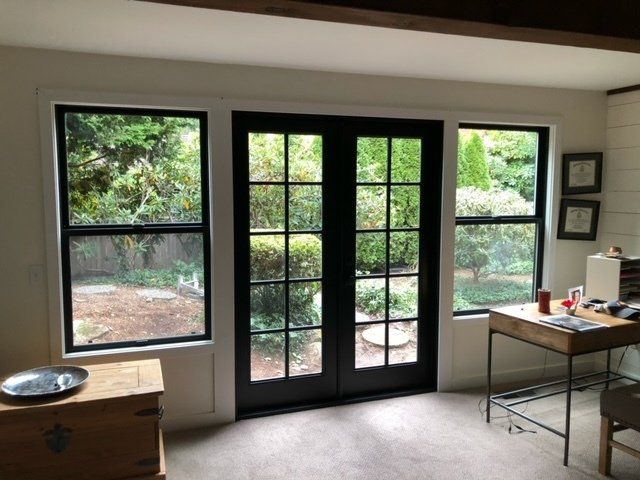 A room with a desk and two windows with a black door — Tukwila, WA — Bel-Red Windows & Doors