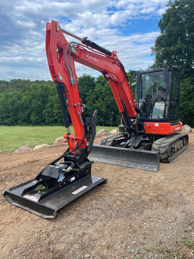 A red excavator is sitting on top of a dirt field.