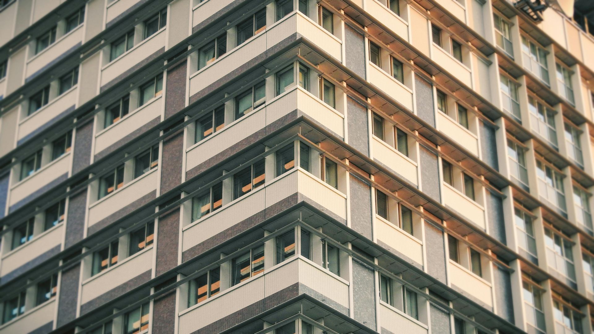 Exterior view of a multi-story building with rows of windows, corner view.