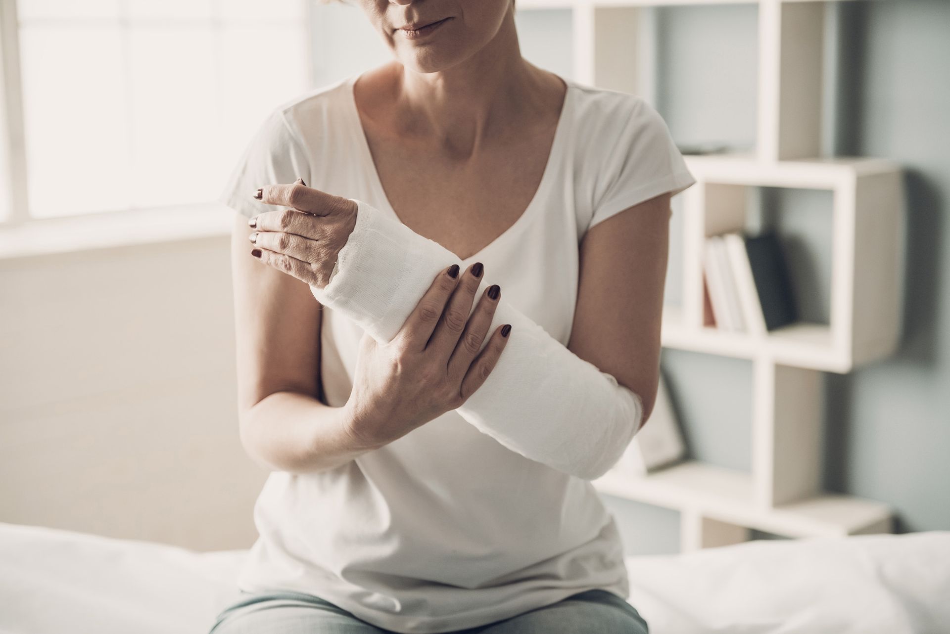 Woman with arm in white cast, sitting indoors.