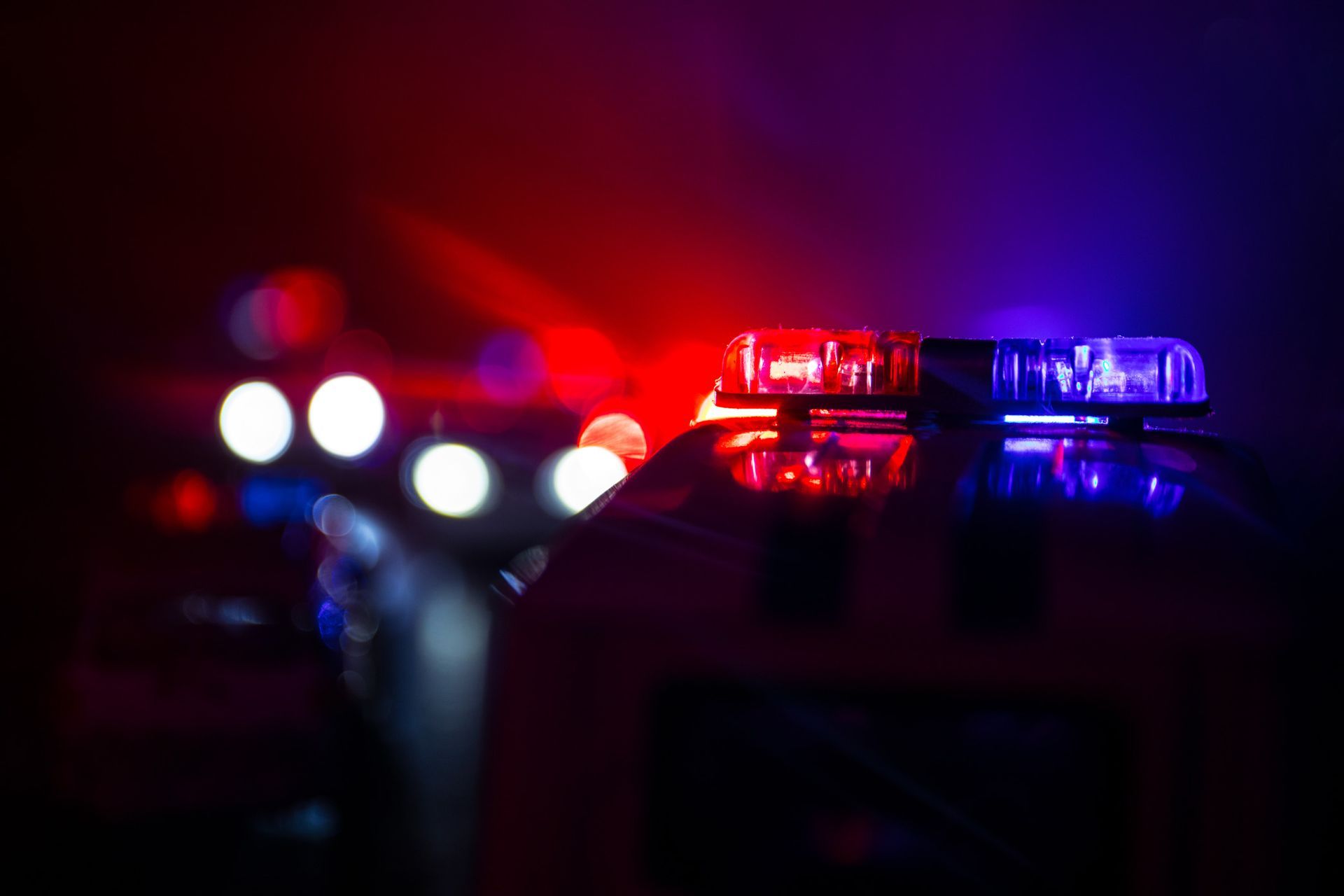 Police car with flashing red and blue lights at night.