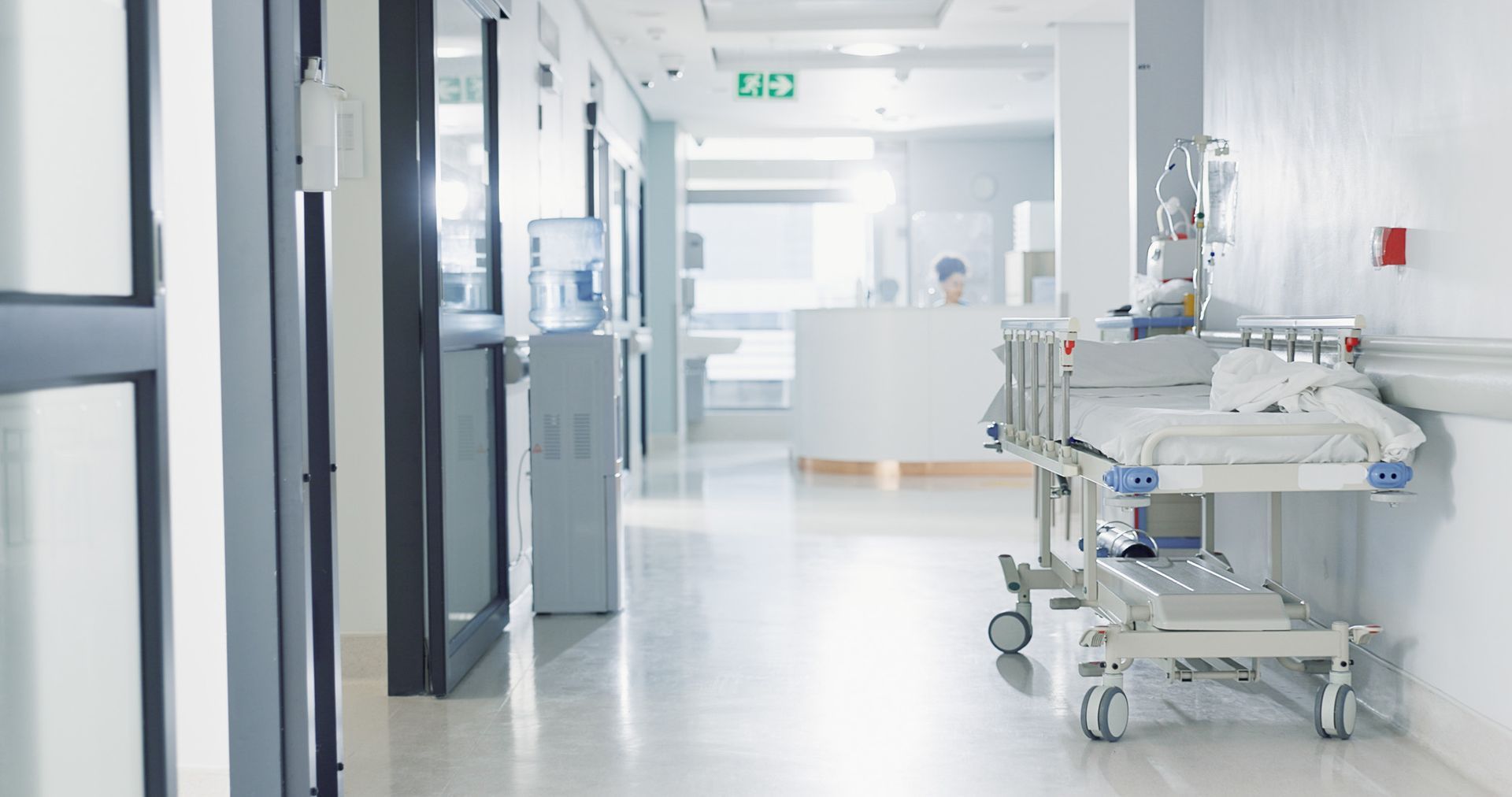 Hospital corridor with an empty gurney; bright, sterile environment.