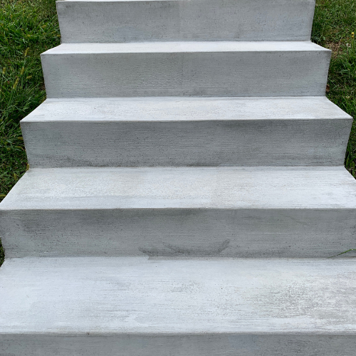 Gray concrete outdoor stairs, leading upwards, surrounded by green grass.