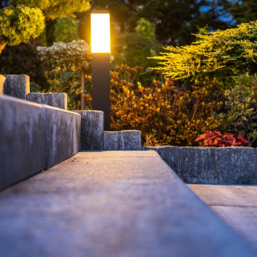 Outdoor steps leading to a garden illuminated by a tall, glowing light post.