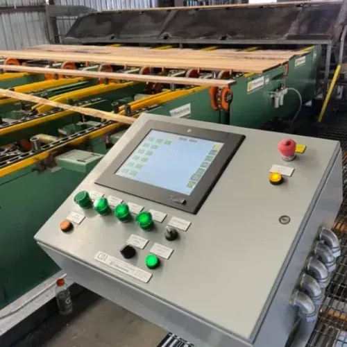 Control panel with a screen and buttons, next to a lumber processing machine.