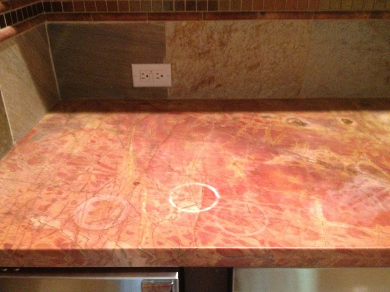 A kitchen counter with a marble counter-top with ring marks and etch marks.