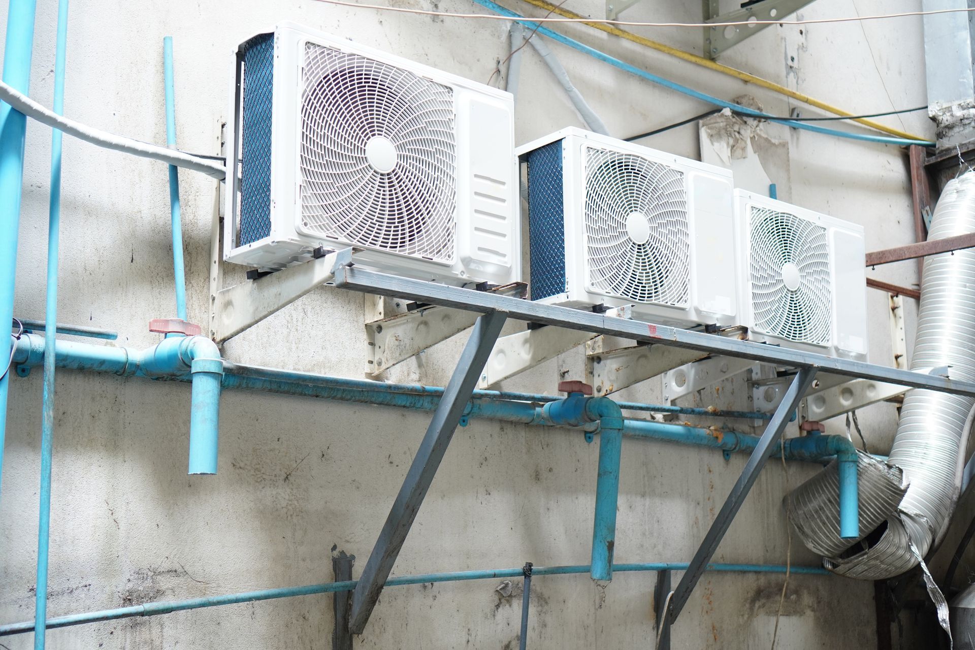 Three outdoor AC units mounted on wall brackets needing commercial appliance repair service.