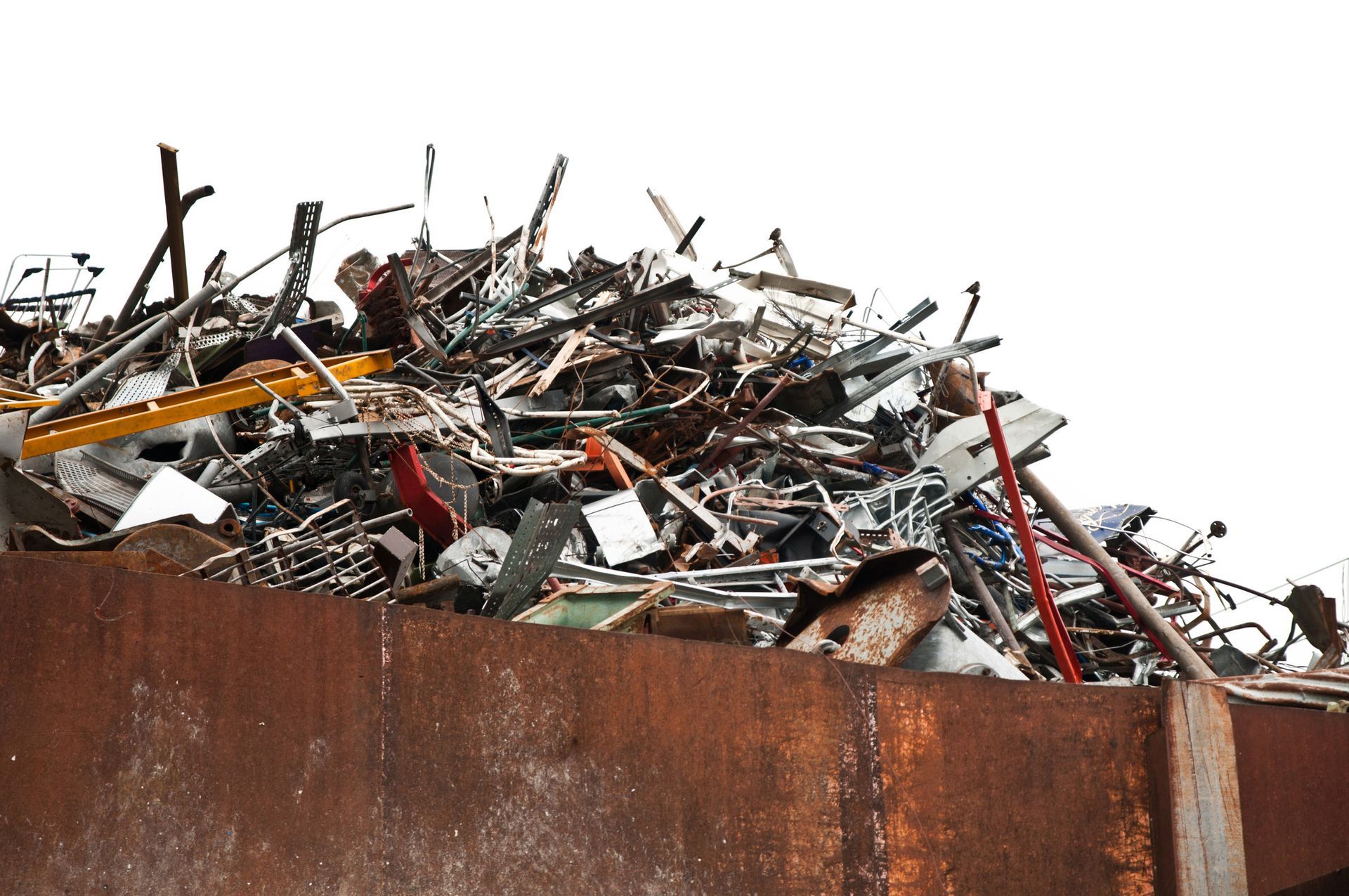 A pile of scrap metal overflowing from a rusty metal container, against a white background.