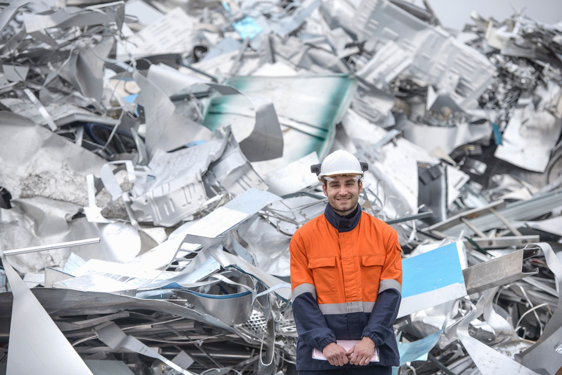 A portrait of worker standing in front of scrap in aluminium recycling plant. A portrait of worker standing in front of scrap in aluminium recycling plant.