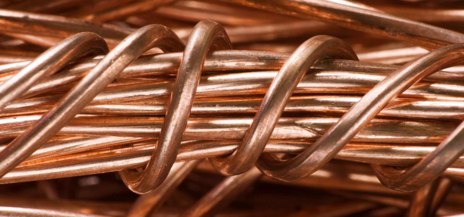 Close-up of twisted copper wire, showing a spiral pattern of bright orange-brown metal.