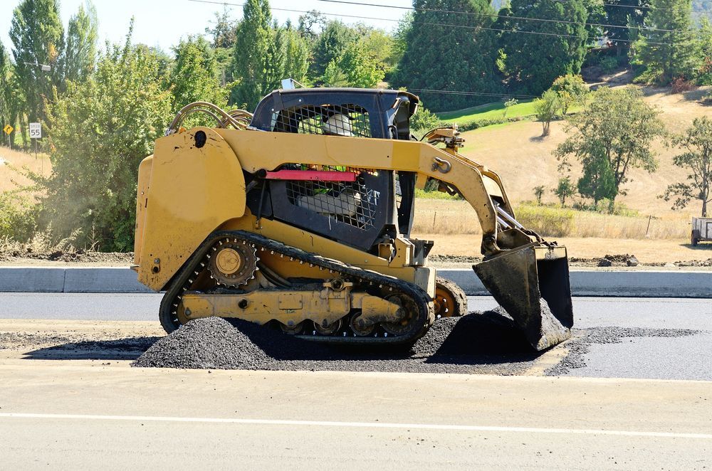 Yellow Skid Steer Placing Asphalt on Road — Hannant Plant Hire in Moranbah, QLD