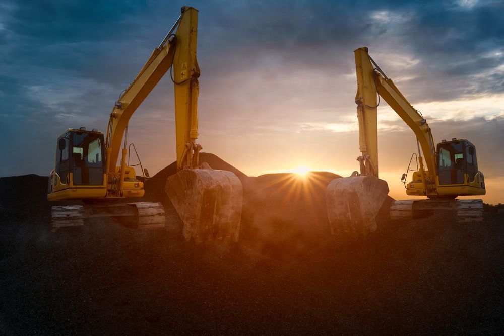 Two yellow excavators digging earth at sunset. — Hannant Plant Hire in Robina, QLD