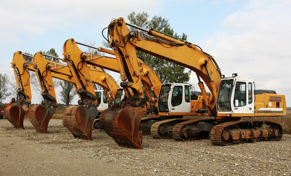 Three Yellow and White Excavators Parked on a Gravel Lot — Hannant Plant Hire in Moranbah, QLD