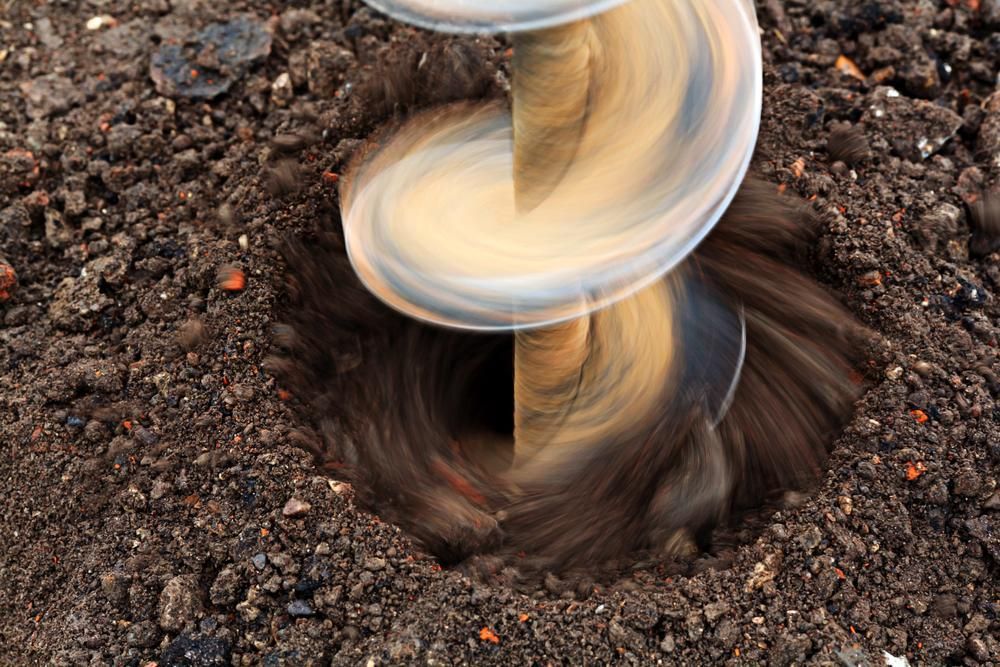 Close Up of a Drill Bit Digging a Hole in the Ground — Hannant Plant Hire in Robina, QLD