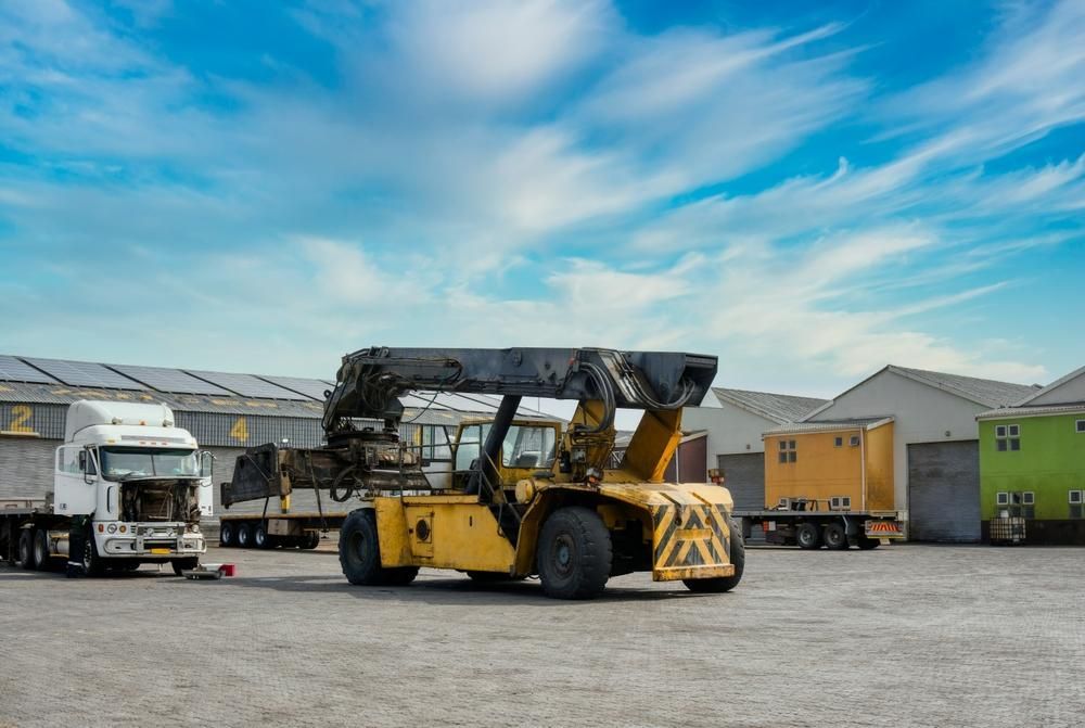 Yellow Forklift is Parked in a Parking Lot Next to a Truck — Hannant Plant Hire in Robina, QLD