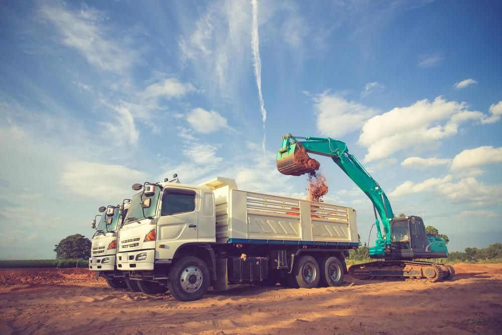 Dump Truck is Being Loaded With Dirt by an Excavator — Hannant Plant Hire in Robina, QLD