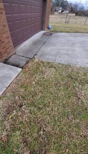A blue and white ball sits on a concrete driveway next to a brown brick house and a garage door.