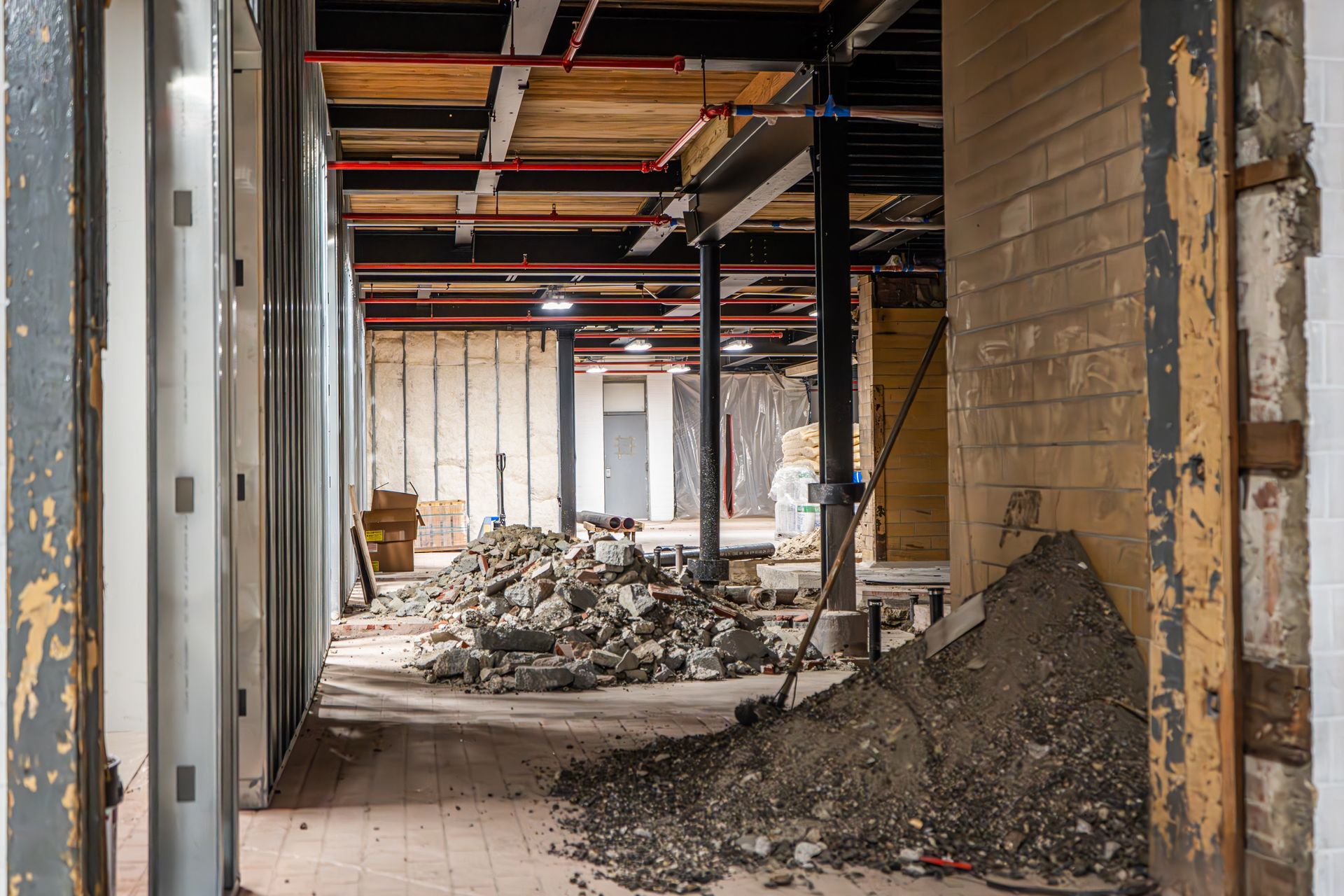 An interior space under construction with piles of rubble, exposed beams, and unfinished walls.