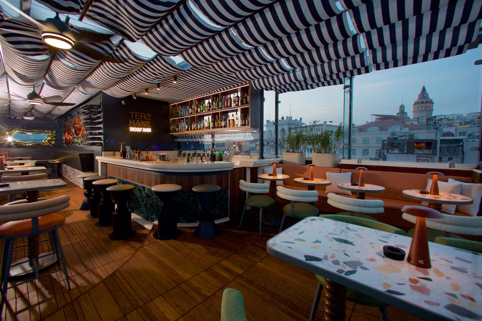 A restaurant with tables and chairs and a striped ceiling.