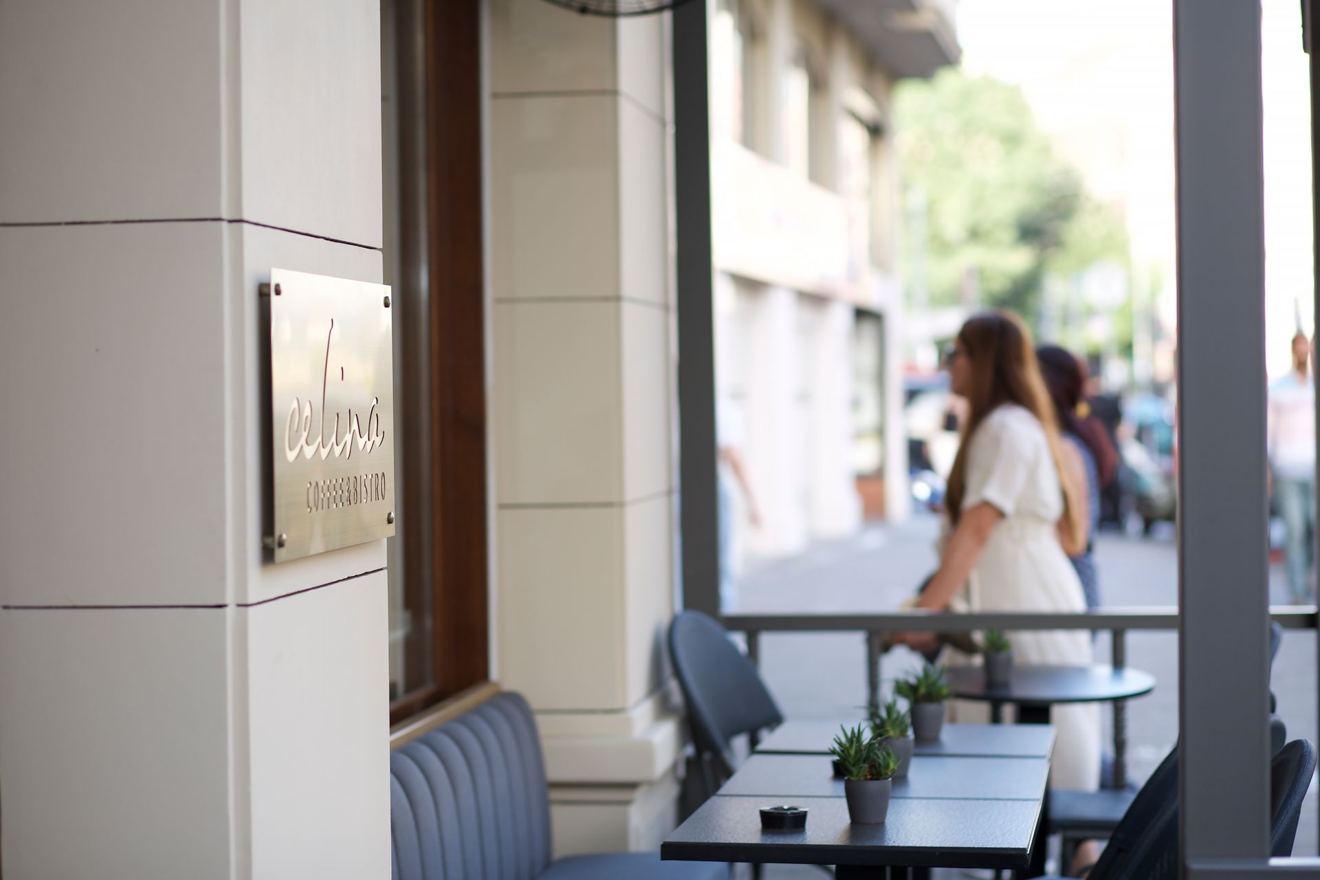 A woman is sitting at a table outside of a restaurant.