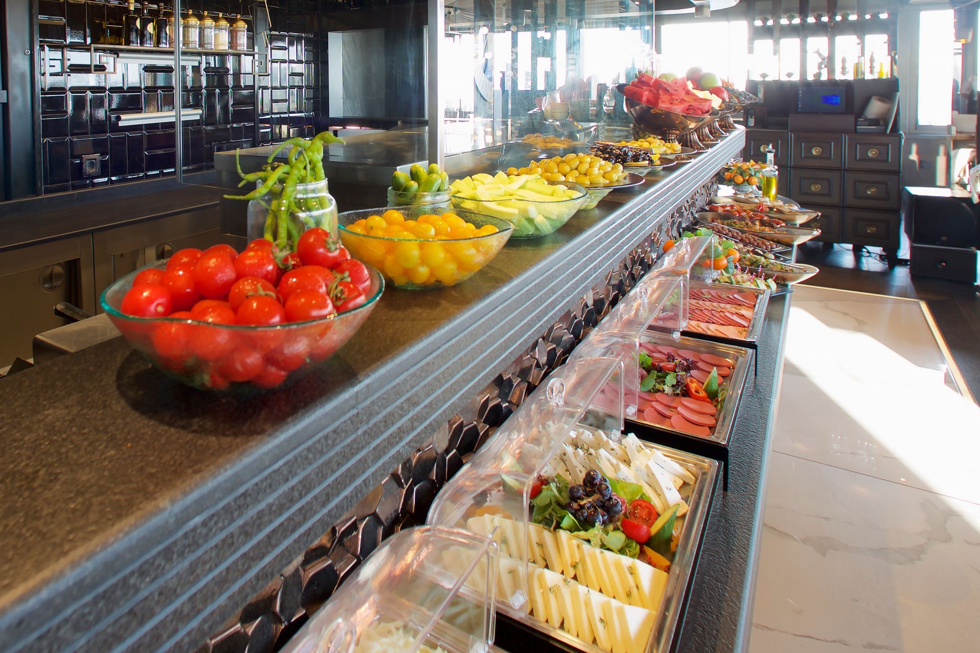A buffet line with a bowl of tomatoes on it