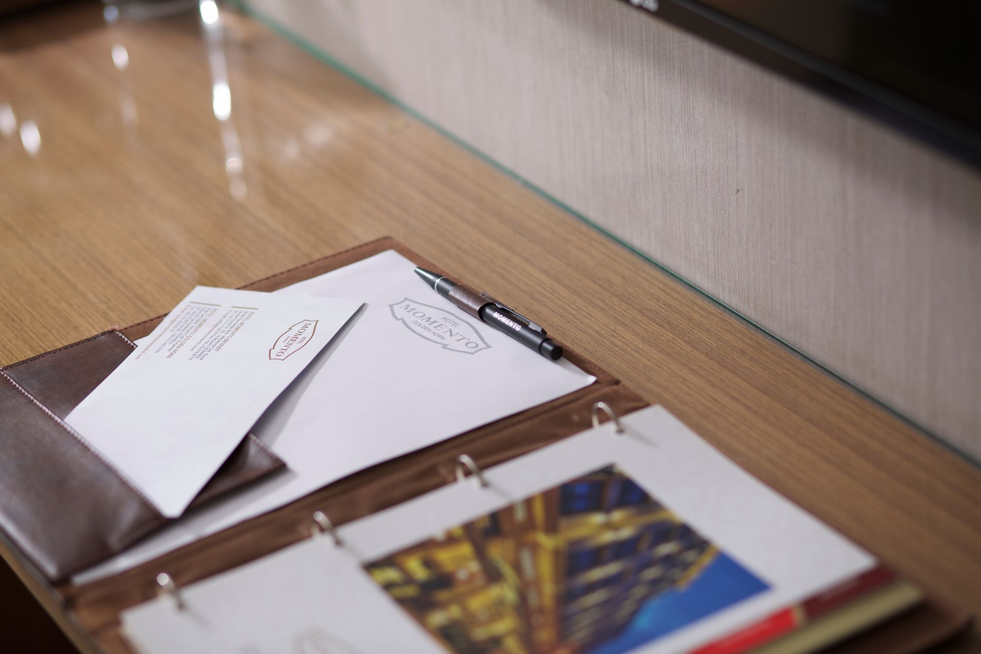 A binder with papers and a pen on a wooden table.