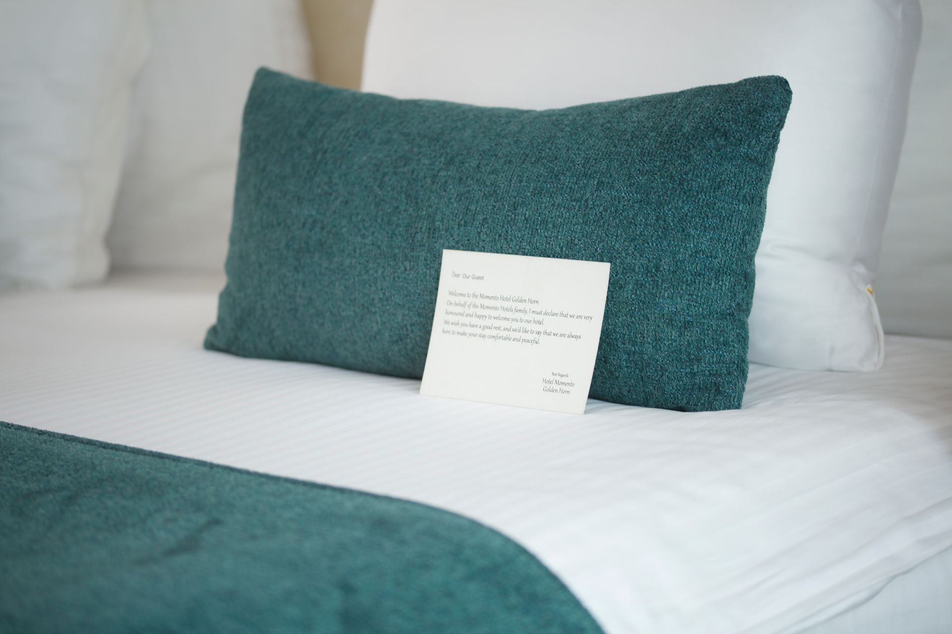 A bed with a blue pillow and a note on it.