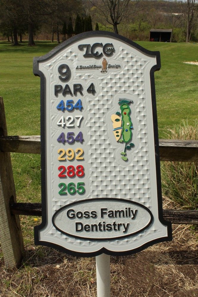 A sign on a golf course says goss family dentistry on it.