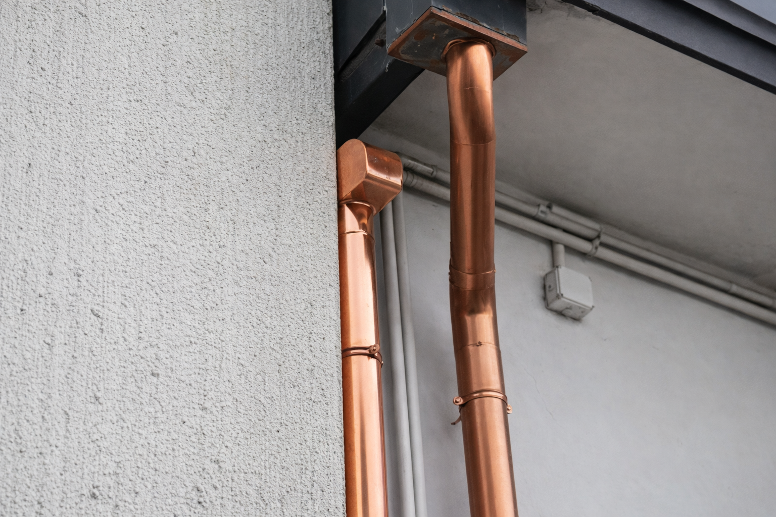 Grondaie in rame fissate a un edificio bianco con finiture nere.