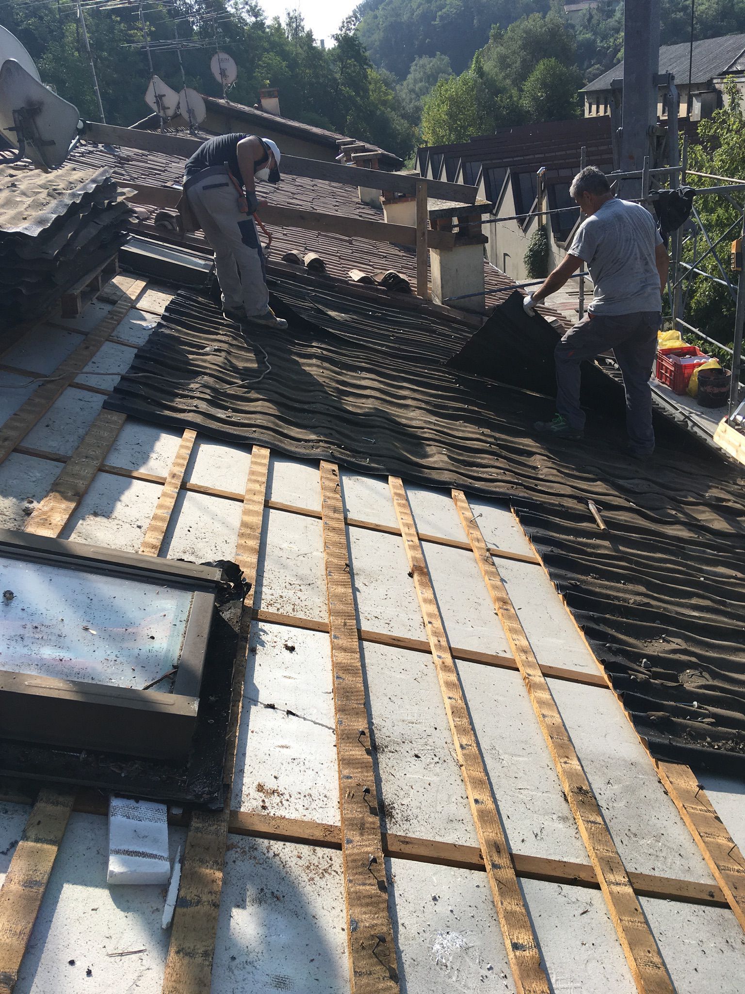 Gru a ponte gialla all'interno di un magazzino. Una rete di sicurezza nera ricopre il soffitto, illuminato da luci intense.