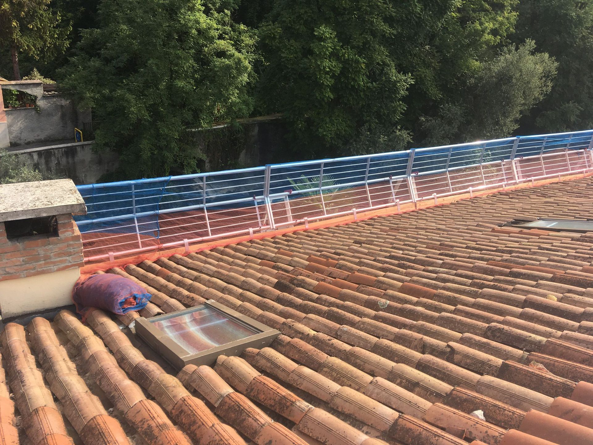 Grondaie marroni su un pilastro di mattoni e sul tetto contro un cielo azzurro.