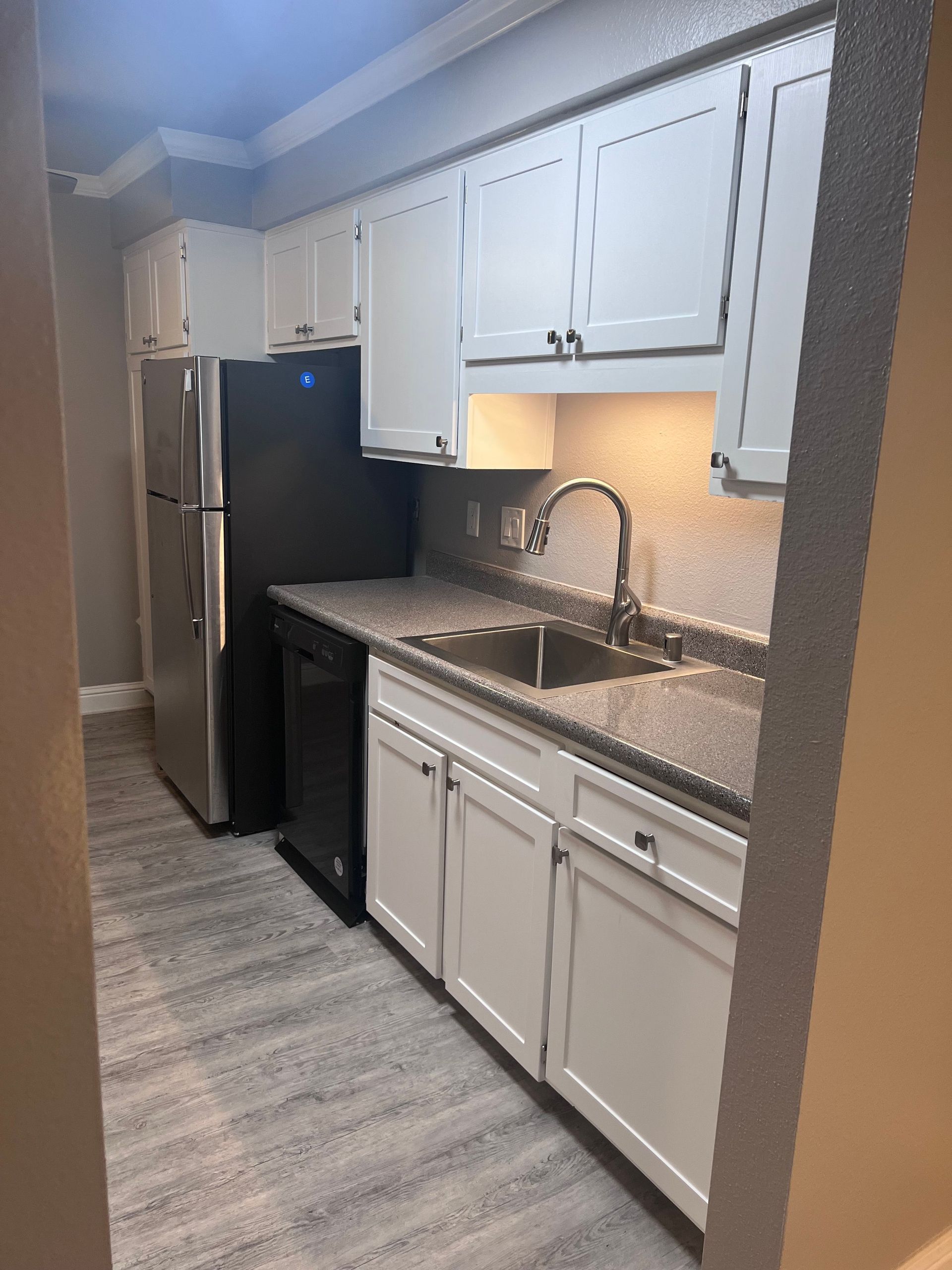 a kitchen with white cabinets and a black refrigerator