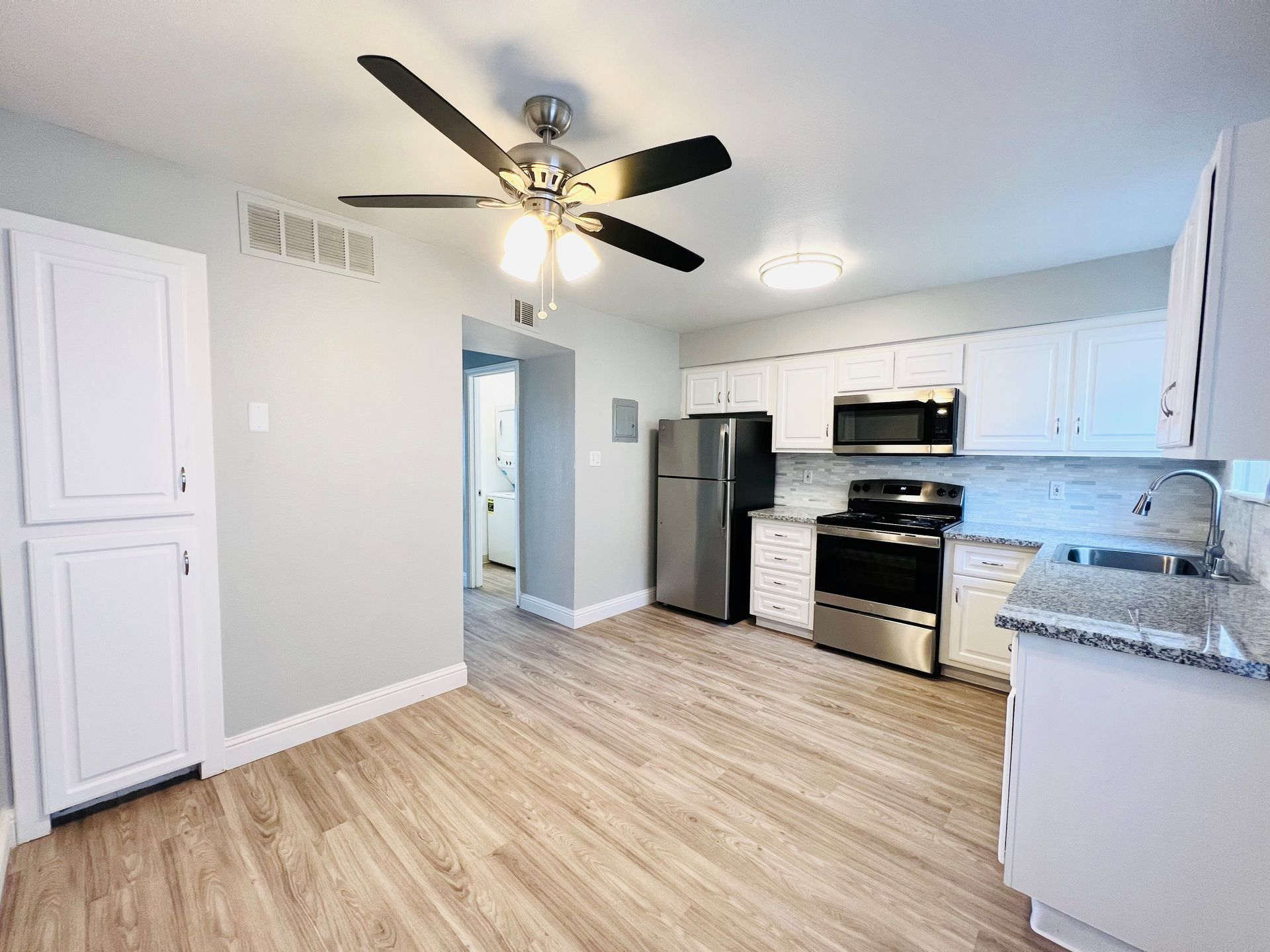 a kitchen with white cabinets stainless steel appliances and a ceiling fan