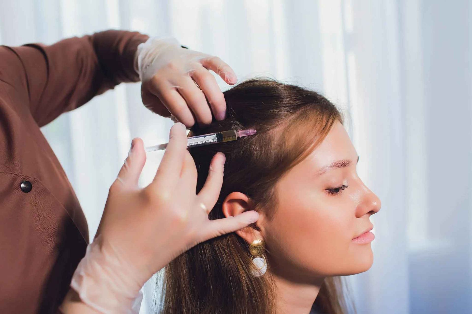 A woman is getting a hair treatment from a hairdresser.