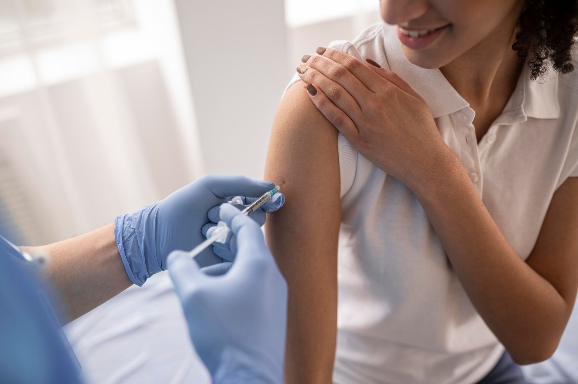 a woman is getting a vaccine in her arm .