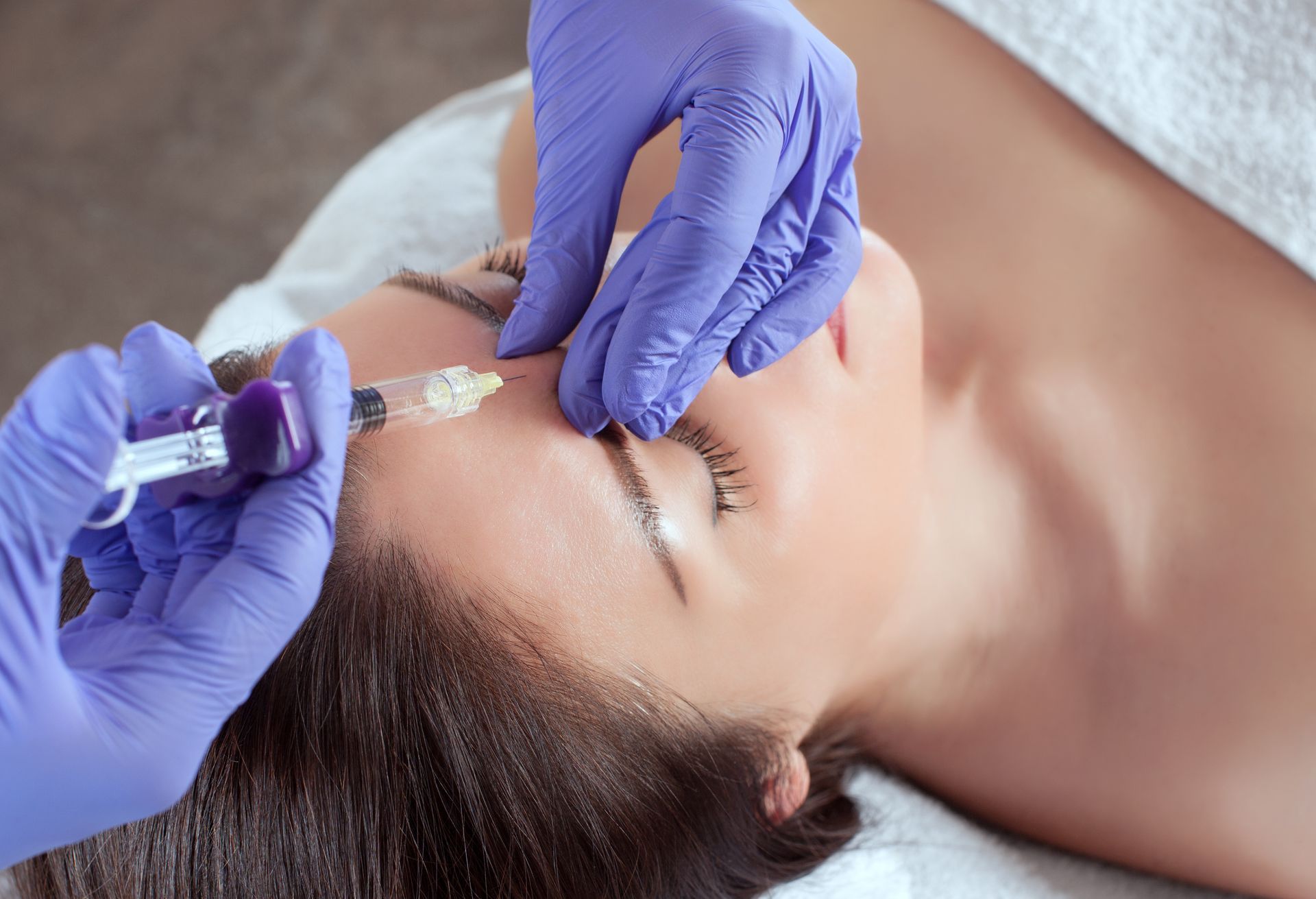 a woman is getting a botox injection in her forehead .