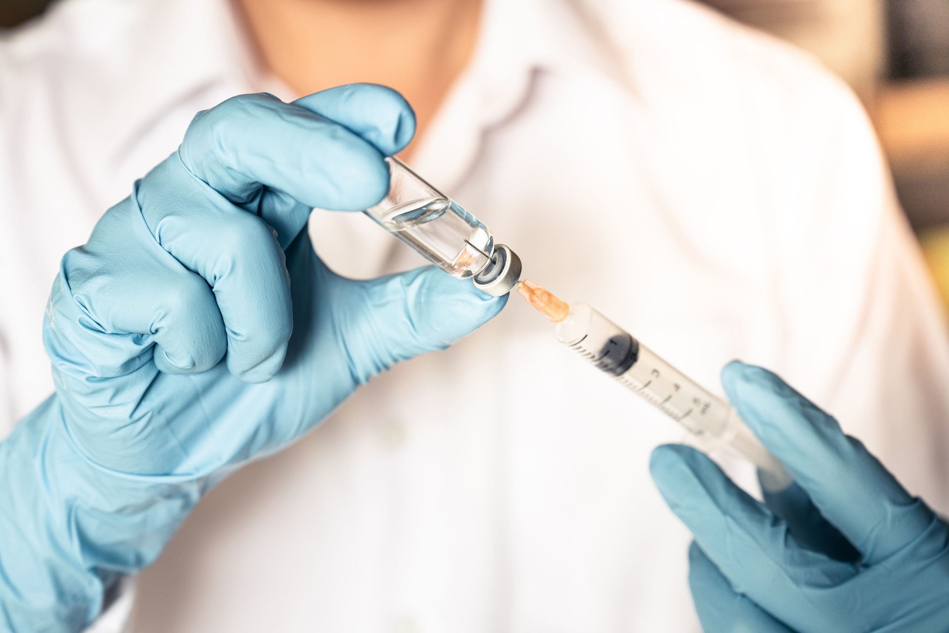 a doctor is holding a syringe and a bottle of vaccine .