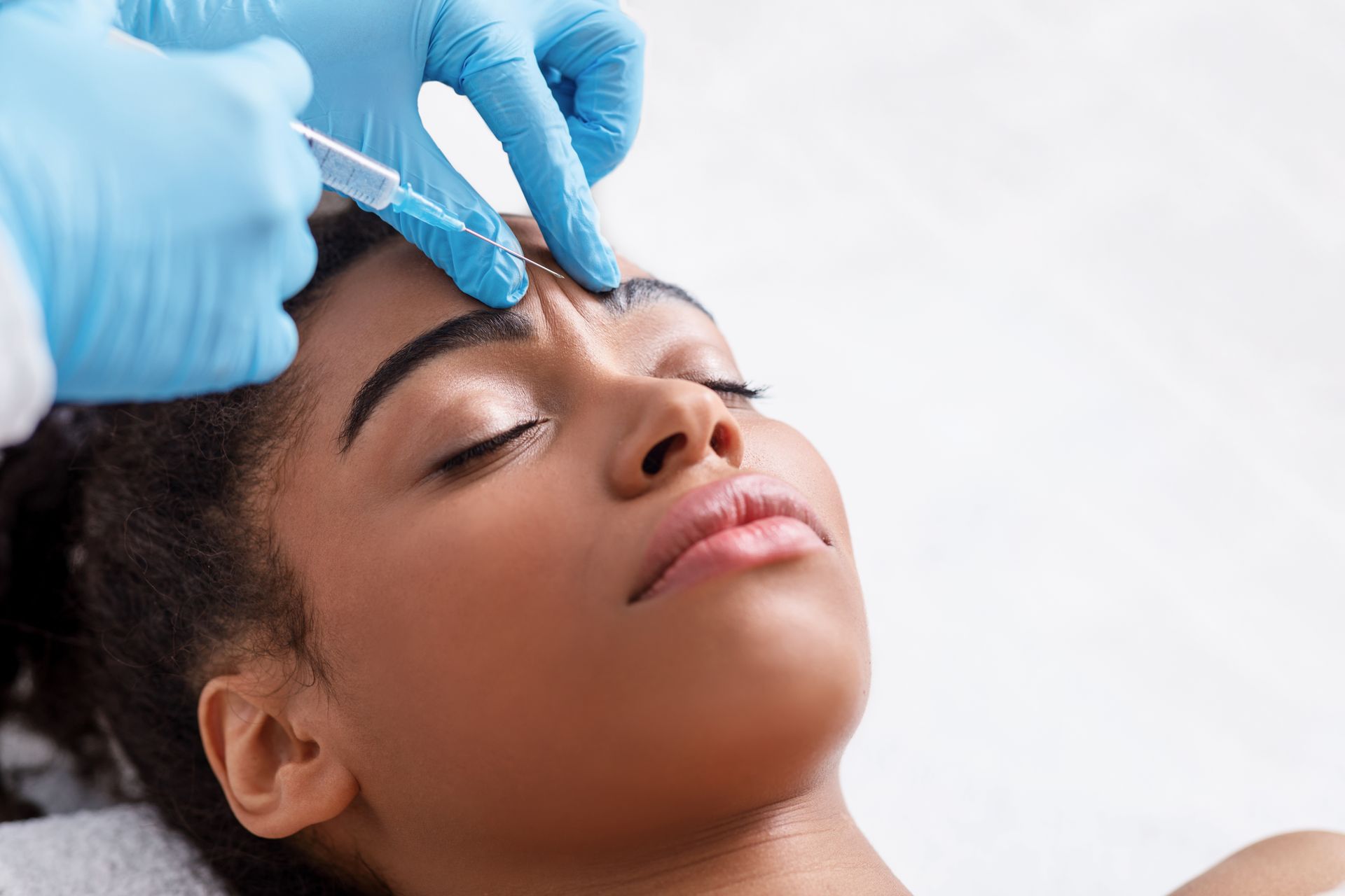 a woman is getting a botox injection in her forehead .